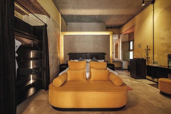 A modern bedroom with a sofa bed, a large bed, and a built-in TV.