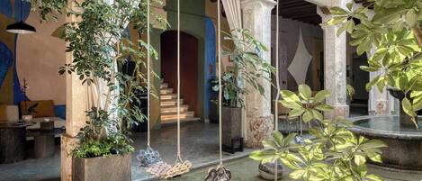 A courtyard with hanging chairs, potted plants, and a fountain.