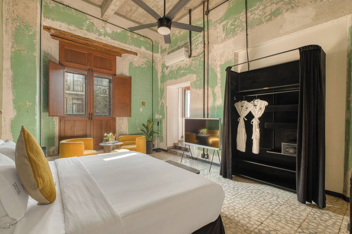 A room with a bed, a ceiling fan, a TV, and a black wardrobe.