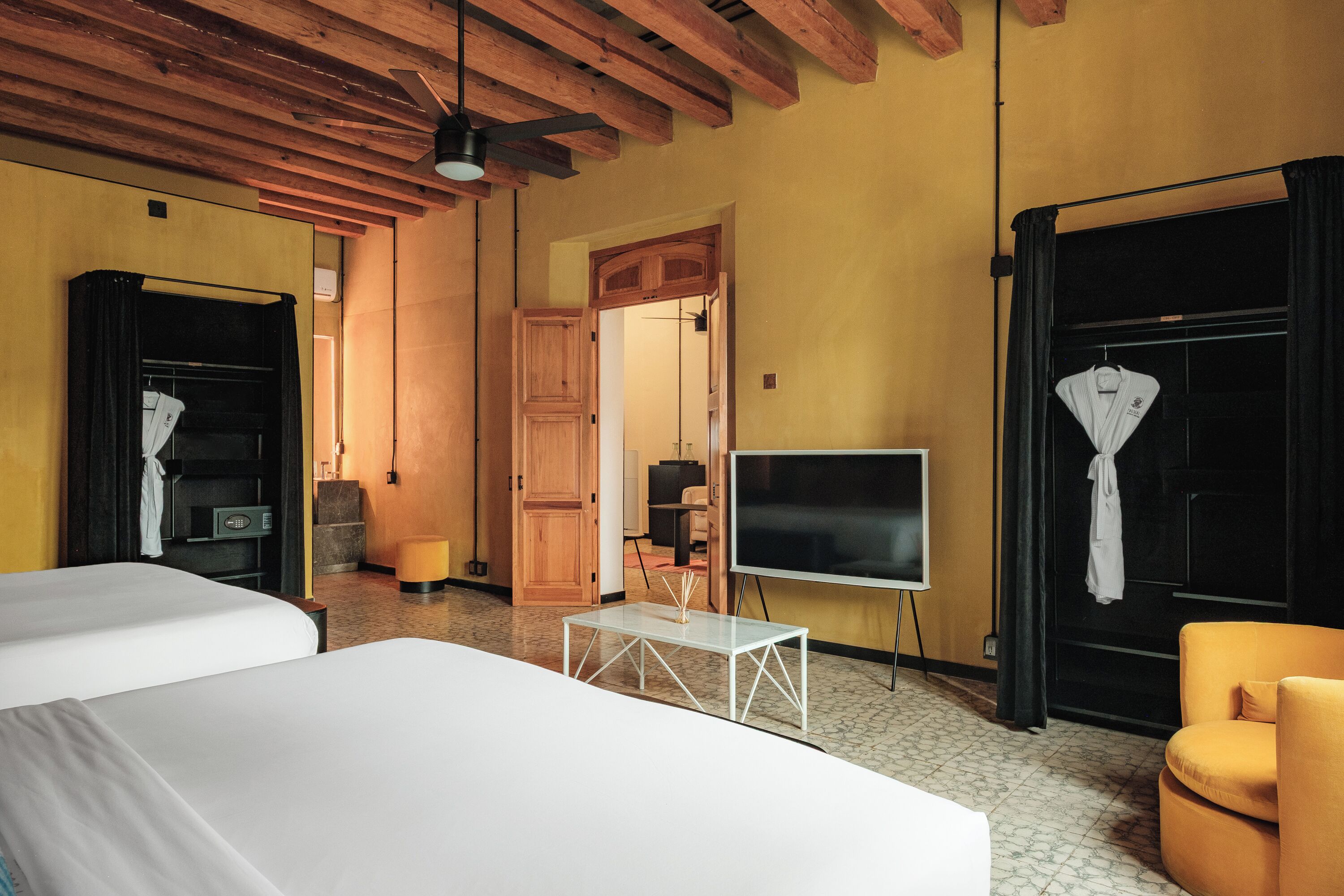 Une chambre d’hôtel avec deux lits, une télévision, un bureau et une grande fenêtre avec des rideaux.