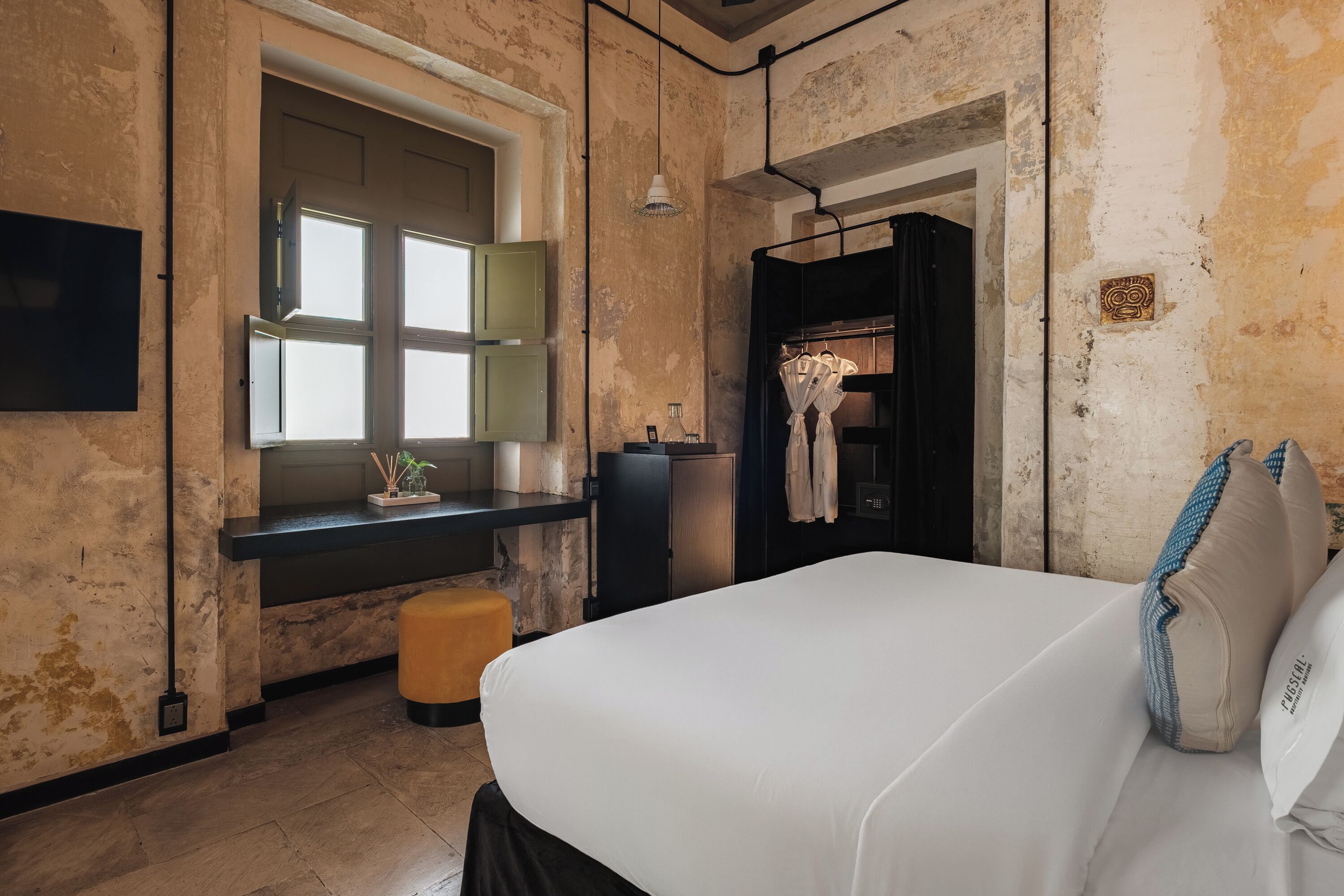 Une chambre d’hôtel avec un grand lit, un bureau avec un miroir, une armoire et une fenêtre.