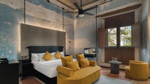 A modern hotel room with a large bed, a sofa, a small table, and a window with a view of trees. - Pug Seal Oaxaca (Oaxaca)