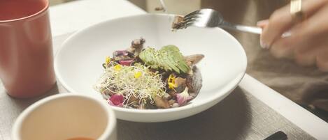 A bowl of food with sprouts, avocado, and other toppings.