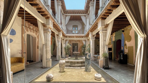 An atrium with a fountain, columns, and a yellow sofa. - Pug Seal Oaxaca (Oaxaca)