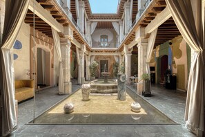 An atrium with a fountain, columns, and a yellow sofa.