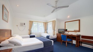 A hotel room with two beds, a desk, a chair, a television, and a ceiling fan. - Cairns Southside International (Cairns)