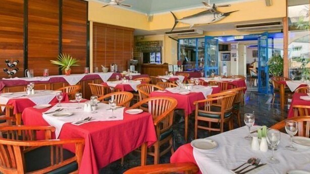A restaurant with multiple tables, ceiling fans, and hanging lights. - Cairns Southside International (Cairns)