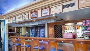 A bar area with wooden bar stools and a counter displaying various bottles. - Cairns Southside International (Cairns)