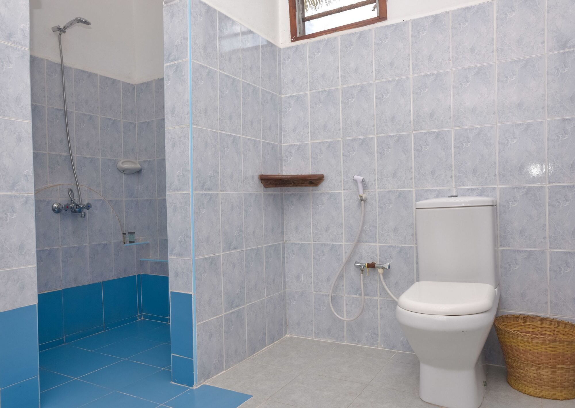 Ein Badezimmer mit Dusche, Toilette und blau gefliestem Boden.
