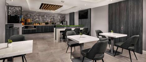 Un restaurante moderno con zona de bar, sillas grises y una mesa de mármol blanco.