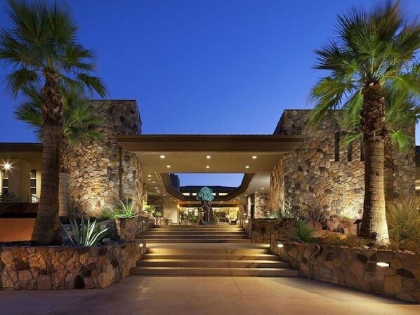 Step into a warm and inviting atmosphere at our hotel entrance, surrounded by palm trees and a modern architectural design.