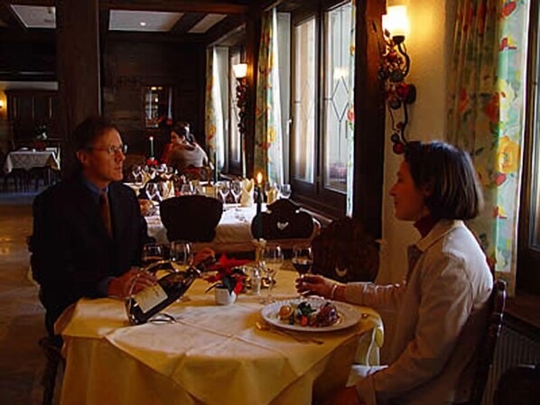 A restaurant with tables set for dining, a waiter, and a customer. - Allalin Relais Du Silence Hotel (Saas-Fee)