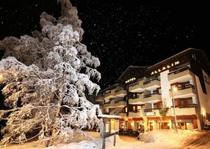 A hotel with multiple balconies and a snow-covered tree in front. - Allalin Relais Du Silence Hotel (Saas-Fee)