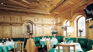 A restaurant with wooden paneled walls, green upholstered booths, and tables set for dining. - Impuls Hotel Tirol (Bad Hofgastein)