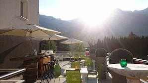 An outdoor patio with tables and chairs, umbrellas, and a bar area. - Impuls Hotel Tirol (Bad Hofgastein)