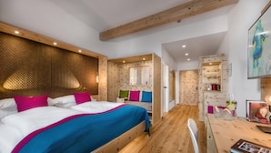A modern bedroom with a large bed, wooden headboard, and a small desk area with a chair. - Impuls Hotel Tirol (Bad Hofgastein)