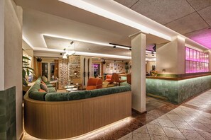A hotel lobby with a curved seating area, a reception desk, and a stone accent wall. - Impuls Hotel Tirol (Bad Hofgastein)