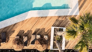 Vue aérienne d’une terrasse en bois avec une piscine, des chaises longues et un jardinier planté de végétaux.
