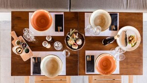 Une table à manger dressée avec des assiettes, des verres et une planche en bois sur laquelle sont disposés des aliments.