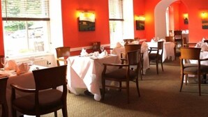 Un restaurante con paredes rojas, manteles blancos y sillas de madera.