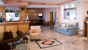 Een hotellobby met een bar, zithoeken en een televisie.