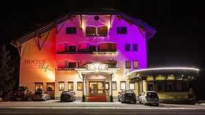 A multi-story hotel with a prominent entrance and a sign reading "HOLZER." - Berghotel Kitzbuhler Alpen (Jochberg)