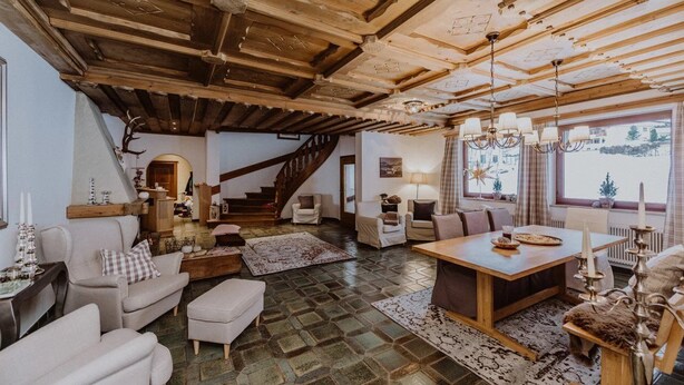 Un salón espacioso con techo de madera, una escalera y un amplio ventanal con vistas al exterior.
