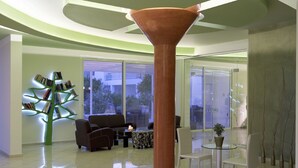 Un interior moderno con una columna central, una estantería, un sofá y una mesa de vidrio.