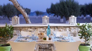 Mesa para dos con vista al mar y olivos al fondo.
