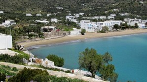 Un pueblo costero con edificios blancos, una playa y montañas al fondo.