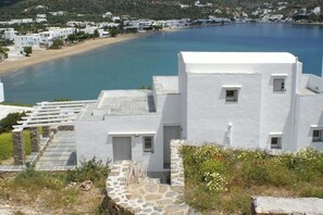 A white building with a stone staircase and a view of a coastal area. - Akrotiraki (Mykonos)