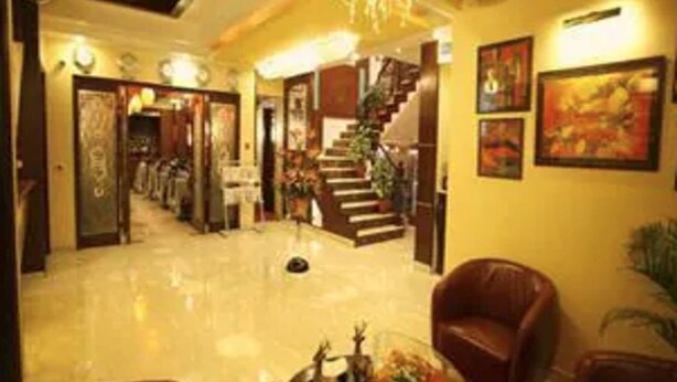 A hotel lobby with a polished floor, a staircase, and artwork on the walls. - Star Grand Villa (New Delhi)