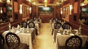 A restaurant with long tables and chairs, wooden walls, and hanging lights. - Star Grand Villa (New Delhi)