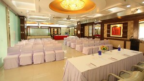 A conference room with rows of white-covered chairs and tables, a large chandelier, and a red carpet. - Star Grand Villa (New Delhi)