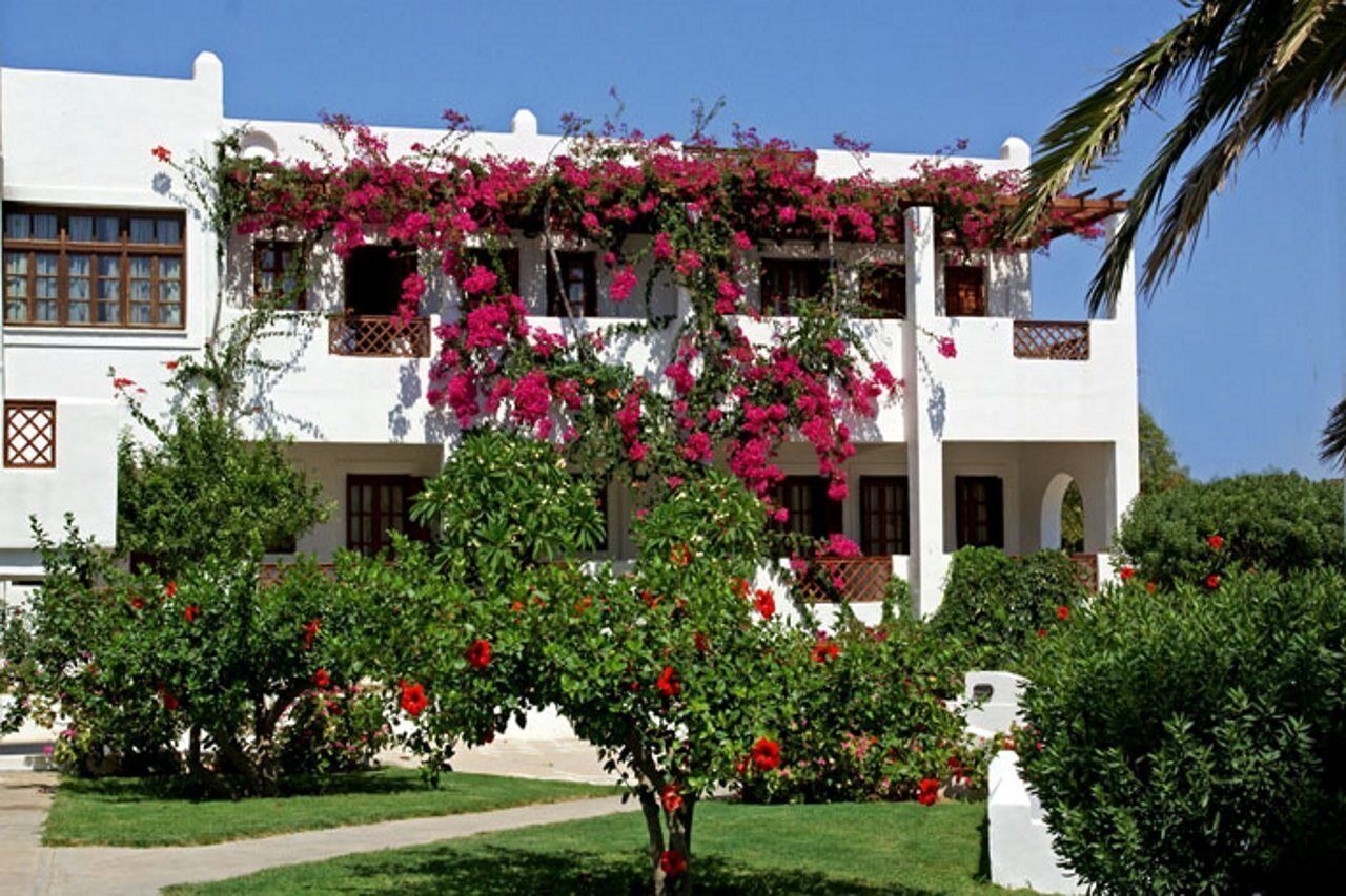 Ein weißes Gebäude mit rosa Blumen und grünem Laub.