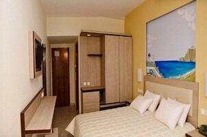 Una habitación de hotel con una cama, un escritorio y un armario.