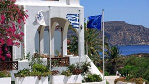 A white building with arches, a flag, and a view of the sea. - Amopi Bay Hotel (Karpathos)