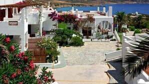 A coastal building with white walls and a stone-paved courtyard. - Amopi Bay Hotel (Karpathos)