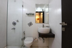 A modern bathroom with a white toilet, a sink with a black countertop, and a shower area. - Kingston Park (New Delhi)