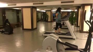 A gym with treadmills, exercise bikes, and a person walking on a treadmill.