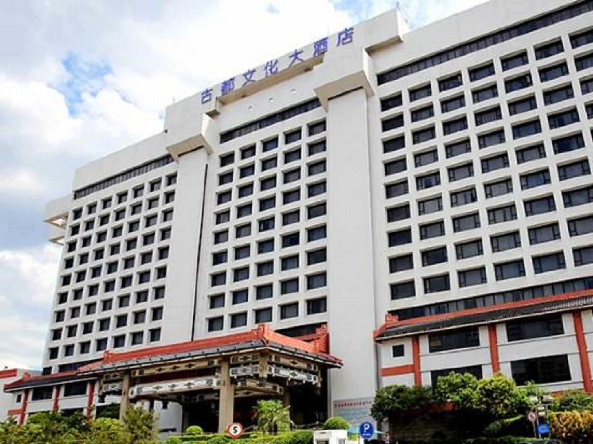 Un gran edificio de hotel con varios pisos y un pabellón de entrada tradicional.