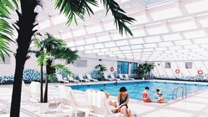 Una piscina interior con sillas de descanso blancas y palmeras.