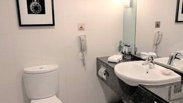 A modern bathroom with a white toilet, a sink with a mirror, and a framed picture on the wall.