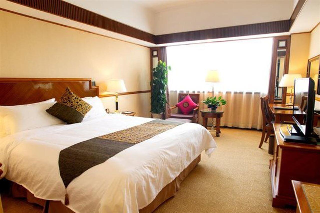 A hotel room with a large bed, two bedside tables, a TV, a desk, and a chair.