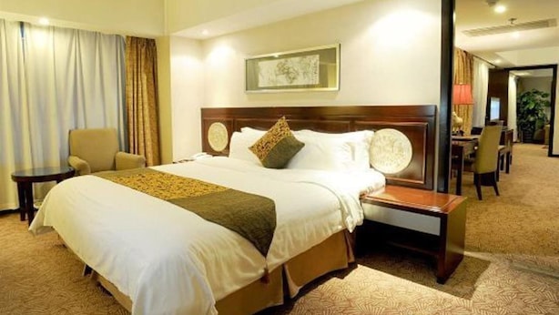 A hotel room with a large bed, a nightstand, a chair, and a desk. - Grand Dynasty Culture Hotel (Xi'an)