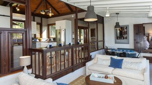 A spacious living area with a large sofa, a coffee table, and a dining area with a table and chairs. - Stunning Views, Peaceful Location, Large Pool & Minutes from Cruz Bay (cruz bay)