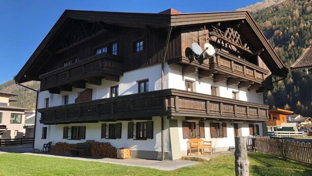 A traditional chalet-style building with a wooden facade, multiple balconies, and a clear view of the surrounding mountainous landscape. - Appartmenthaus Raudaschl (Laengenfeld)