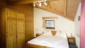 A wooden-paneled bedroom with a bed, nightstands, and a window. - Appartmenthaus Raudaschl (Laengenfeld)