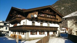 A traditional chalet with a wooden facade, multiple balconies, and a snow-covered ground. - Appartmenthaus Raudaschl (Laengenfeld)