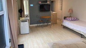 A small, well-lit room with a bed, a desk, a chair, and a TV mounted on the wall. - The Little Jurassic Lake House.<br>keep in mind sometime Satellite TV Doesn’t work. (Carrying Place)